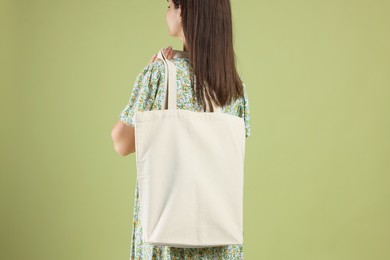 Woman with blank shopper bag on color background, back view. Mockup for design