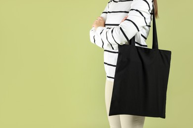 Photo of Woman with blank black shopper bag on color background, closeup. Mockup for design