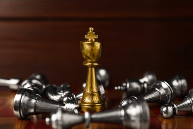 Photo of Golden chess king among fallen silver game pieces on chessboard, closeup. Competition concept