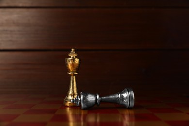 Photo of Golden chess king near fallen silver one on chessboard. Competition concept