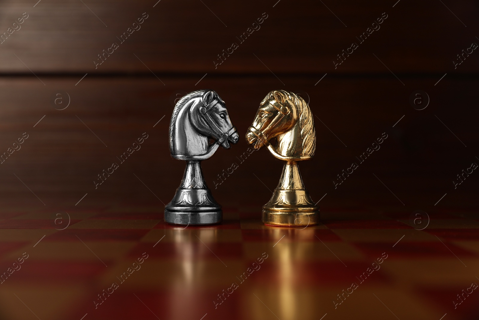 Photo of Golden and silver chess knights in middle of chessboard. Competition concept