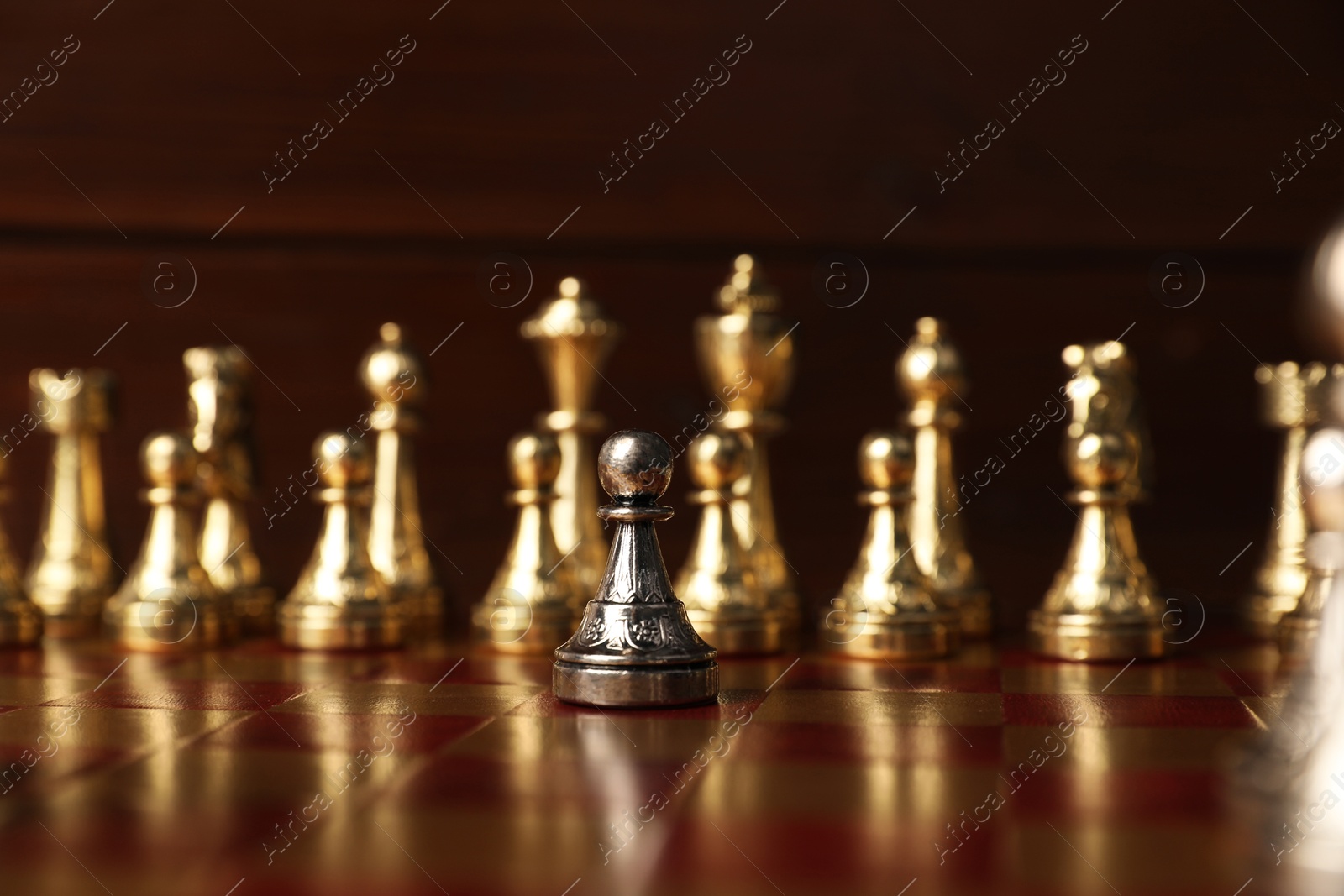 Photo of Silver pawn in front of other chess pieces on chessboard. Competition concept