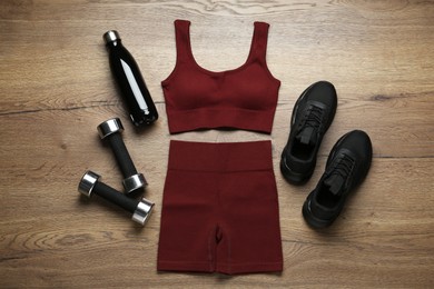 Photo of Flat lay composition with women's sportswear and sneakers on wooden background