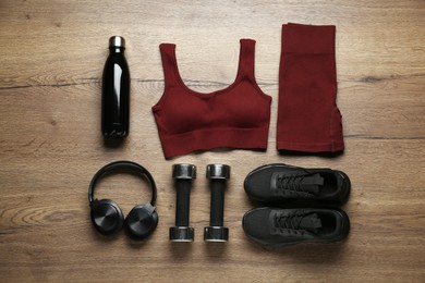 Photo of Flat lay composition with women's sportswear and sneakers on wooden background