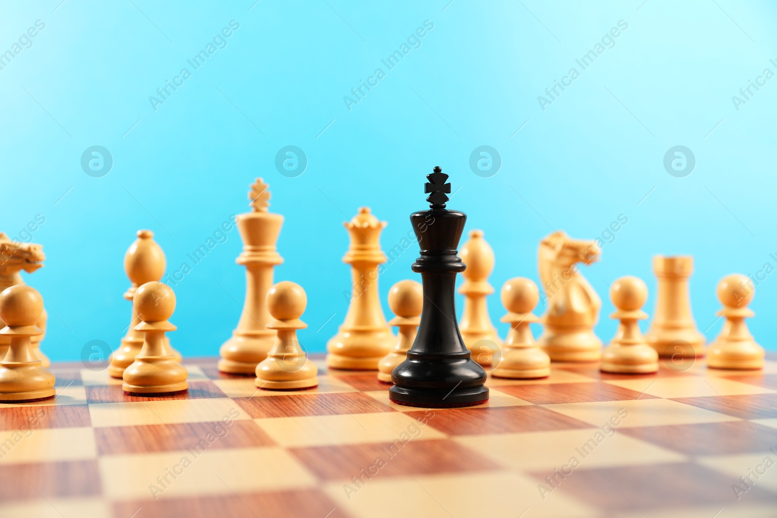 Photo of Black king in front of other white chess pieces on chessboard. Competition concept