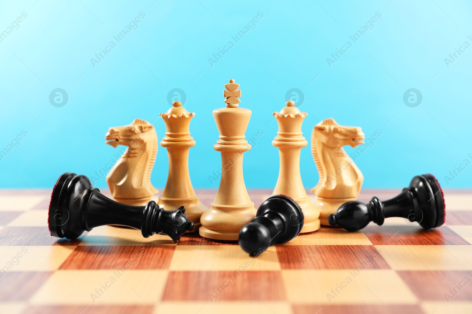 Photo of White chess pieces among other fallen black ones on chessboard. Competition concept