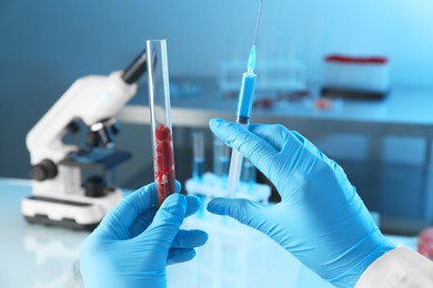 Photo of GMO concept. Scientist with syringe and piece of meat in test tube at laboratory, closeup