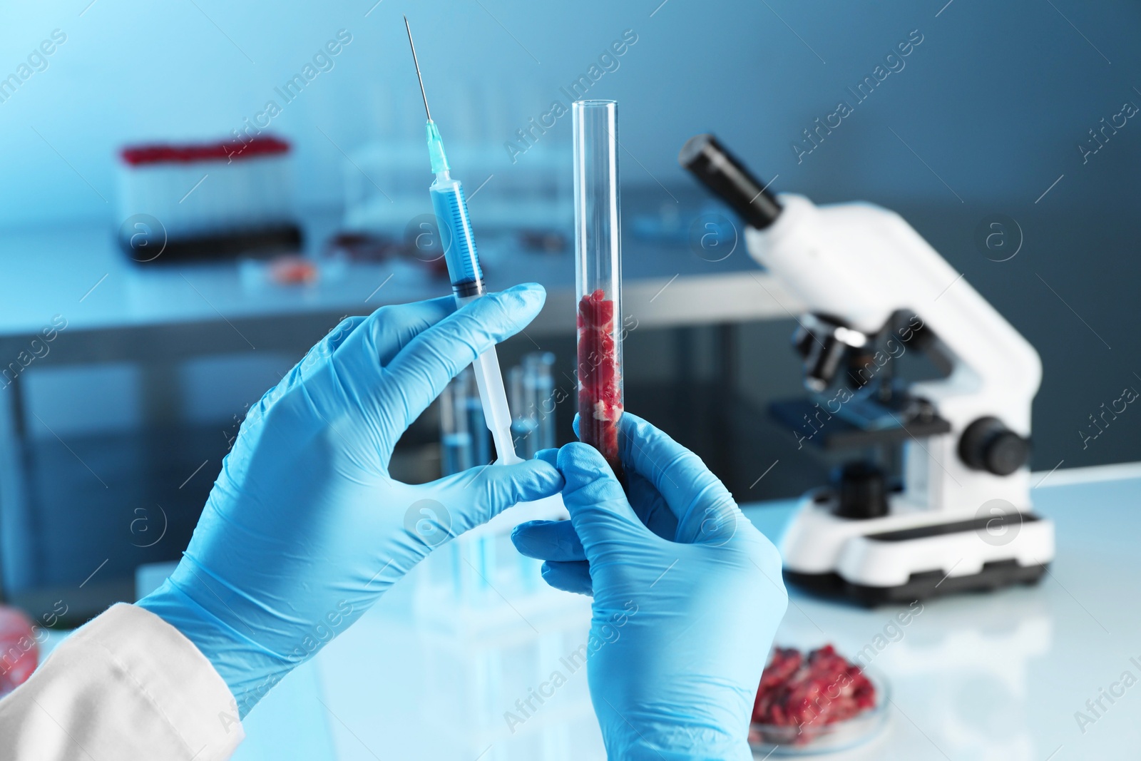 Photo of GMO concept. Scientist with syringe and piece of meat in test tube at laboratory, closeup