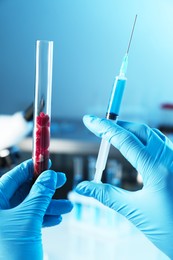 Photo of GMO concept. Scientist with syringe and piece of meat in test tube at laboratory, closeup