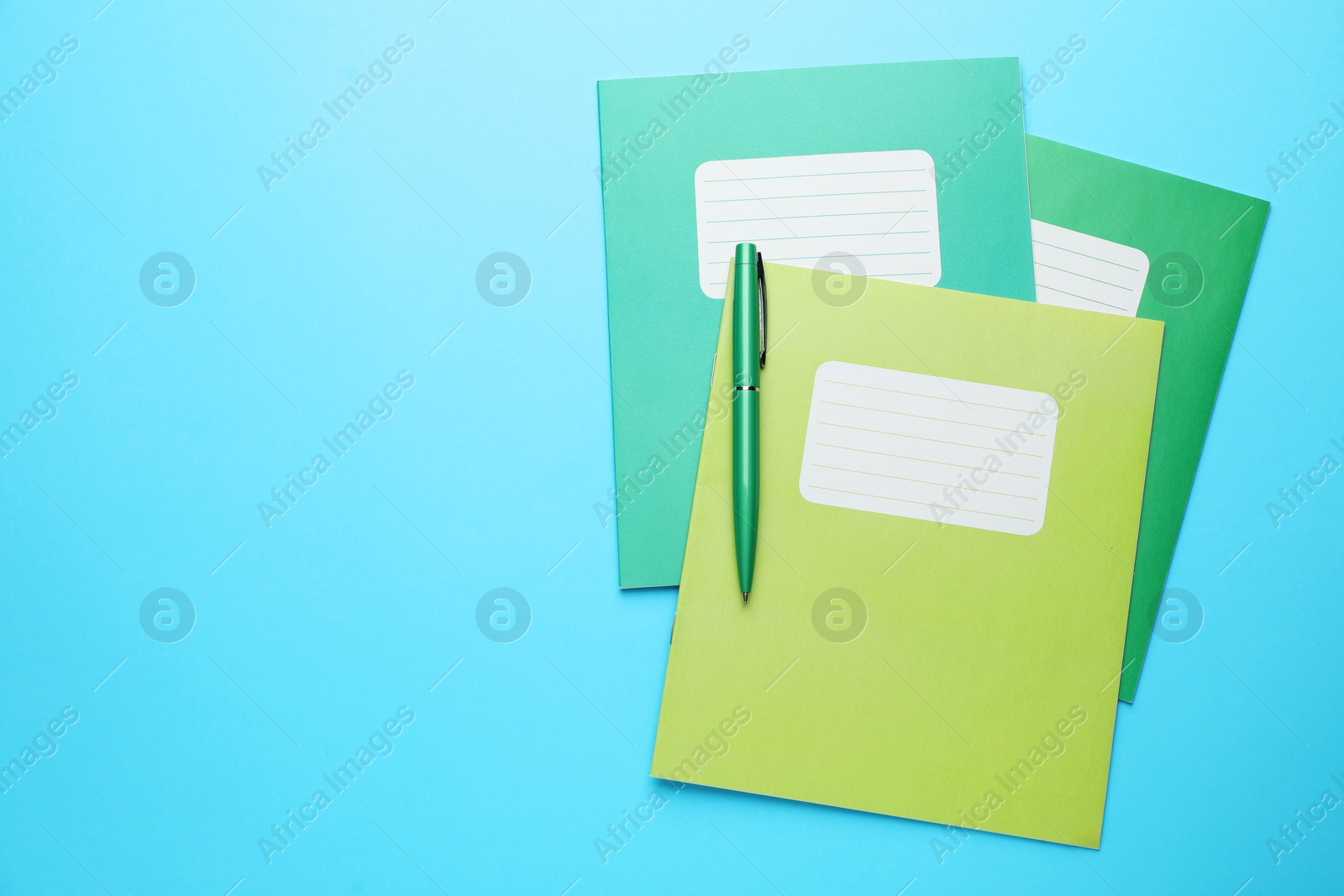 Photo of Copybooks and pen on light blue background, top view. Space for text