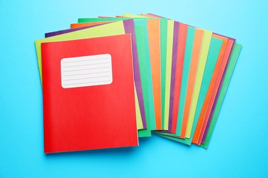 Photo of Colorful copybooks on light blue background, top view. School stationery