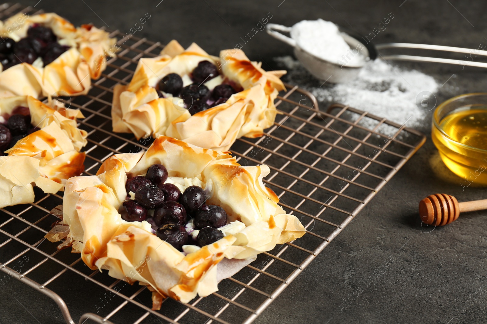 Photo of Delicious puff pastries with blueberries on gray textured table, closeup