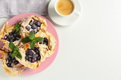 Photo of Tasty puff pastries with blueberries, powdered sugar, mint and coffee on white table, top view. Space for text