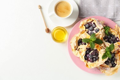 Photo of Tasty puff pastries with blueberries, powdered sugar, mint, honey and coffee on white table, flat lay. Space for text