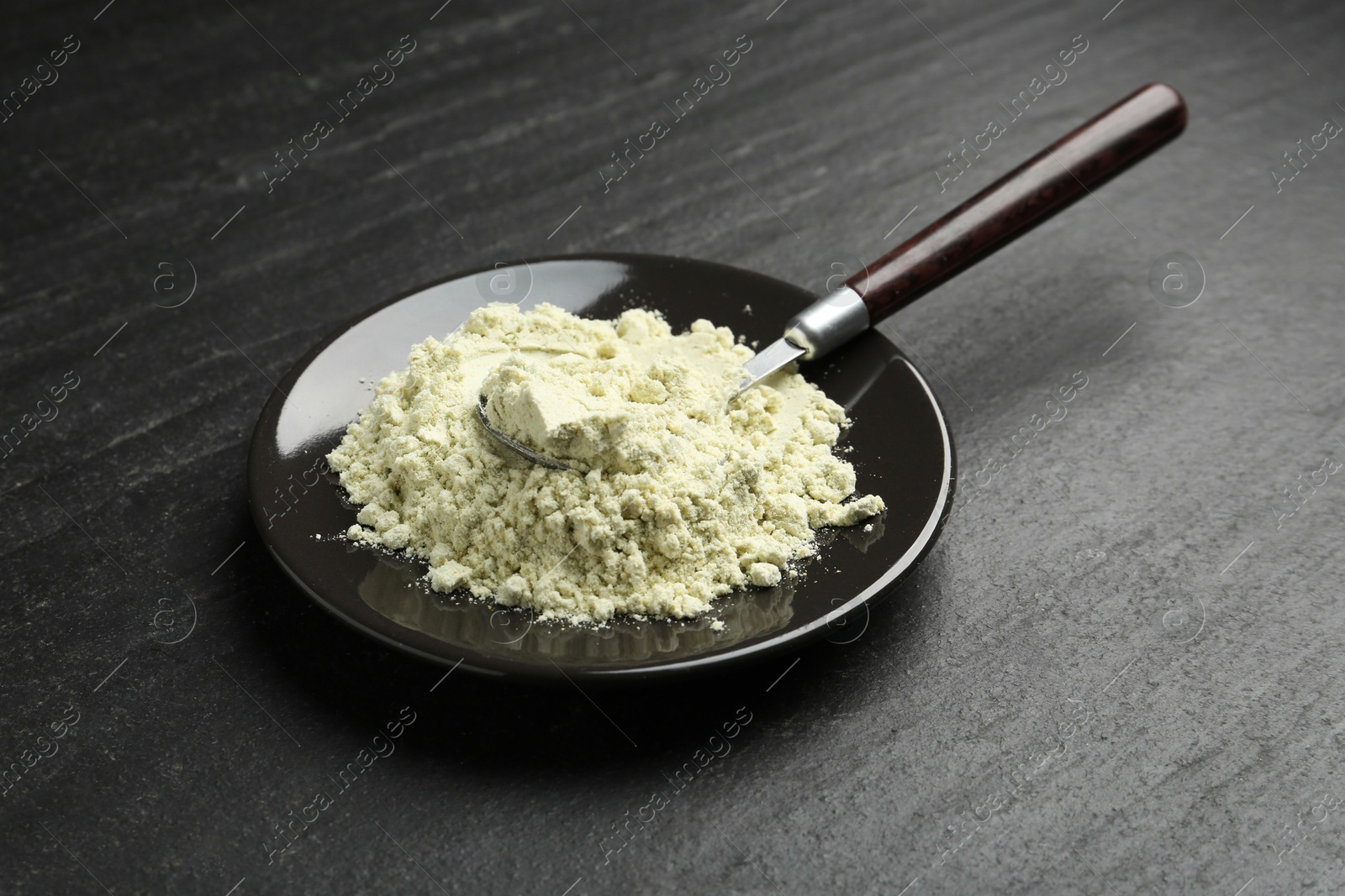 Photo of Plate with dry wasabi powder and spoon on dark textured table