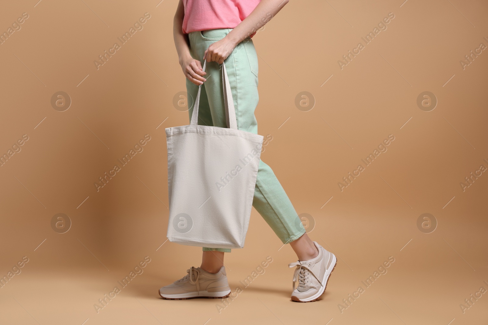 Photo of Woman with blank shopper bag on beige background, closeup. Mockup for design