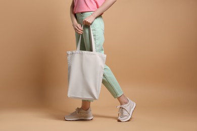 Woman with blank shopper bag on beige background, closeup. Mockup for design