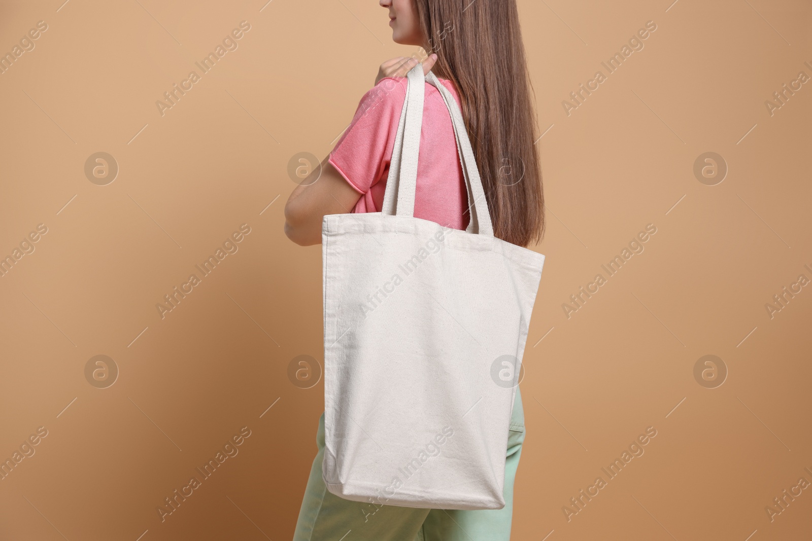 Photo of Woman with blank shopper bag on beige background, closeup. Mockup for design