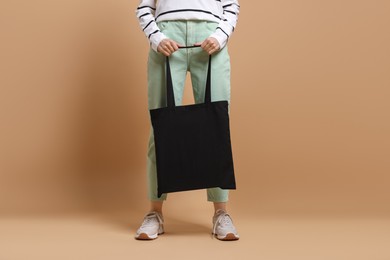 Woman with blank shopper bag on beige background, closeup. Mockup for design