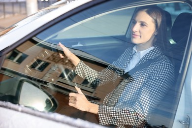 Driver behind steering wheel of modern car, view from outside