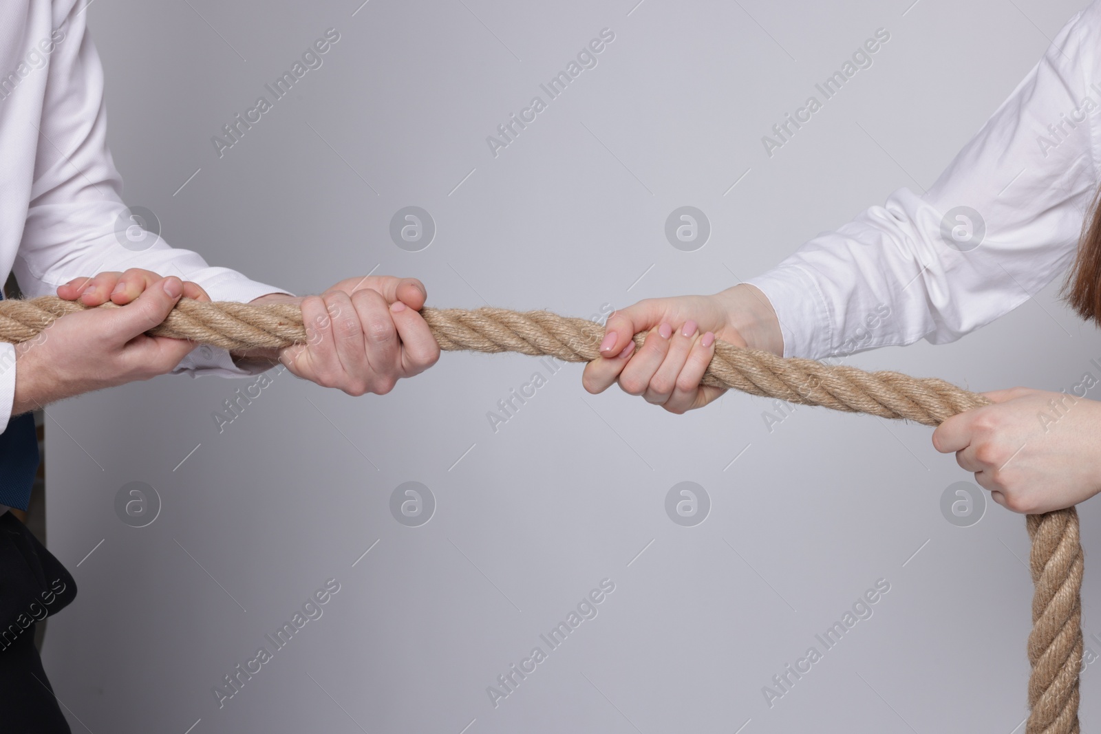 Photo of Competition concept. Businesspeople pulling rope on grey background, closeup