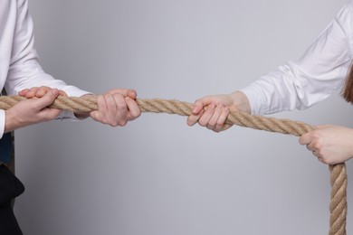 Competition concept. Businesspeople pulling rope on grey background, closeup