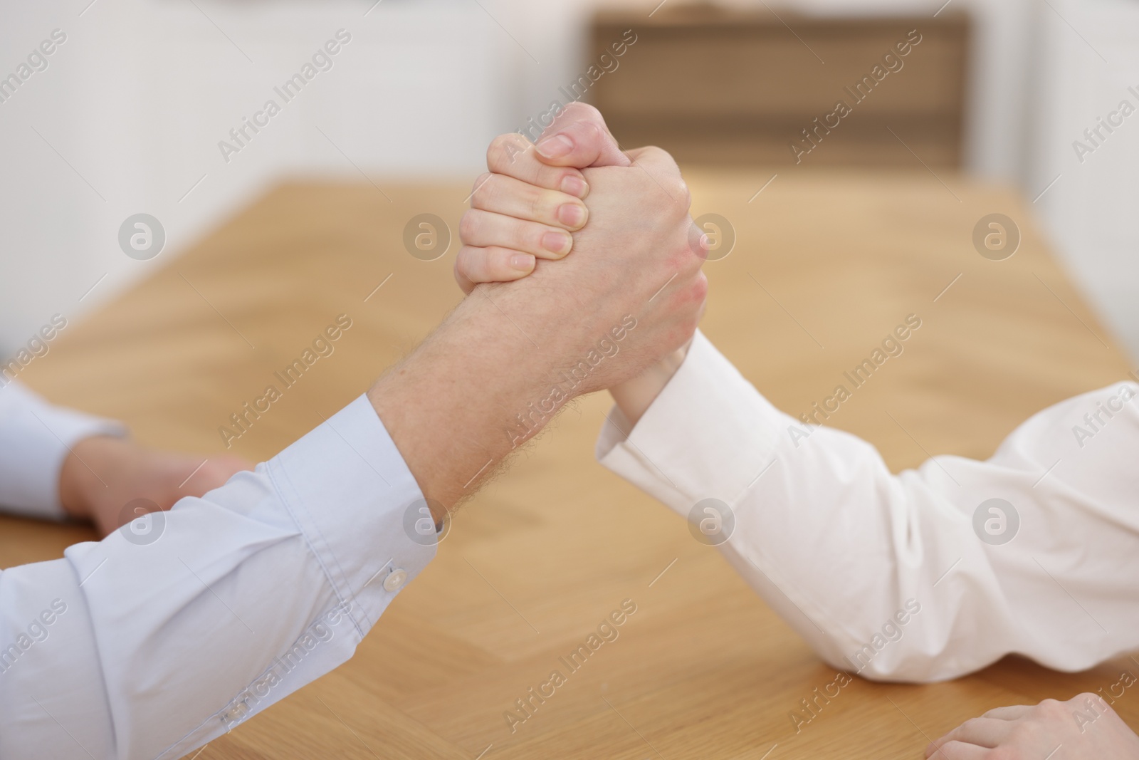 Photo of Competition concept. Businesspeople arm wrestling at table in office, closeup