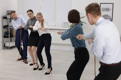 Competition concept. Group of businesspeople pulling rope in office