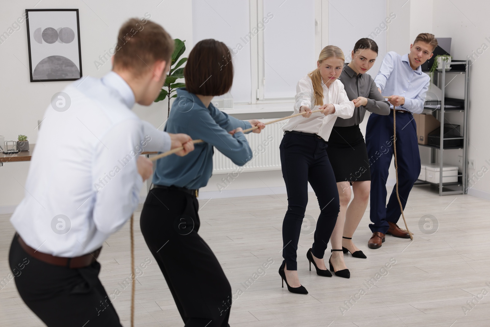 Photo of Competition concept. Group of businesspeople pulling rope in office