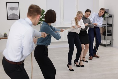 Competition concept. Group of businesspeople pulling rope in office