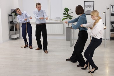 Competition concept. Group of businesspeople pulling rope in office