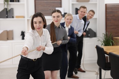 Photo of Competition concept. Group of businesspeople pulling rope in office, selective focus