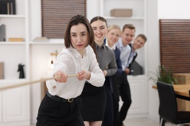 Competition concept. Group of businesspeople pulling rope in office, selective focus