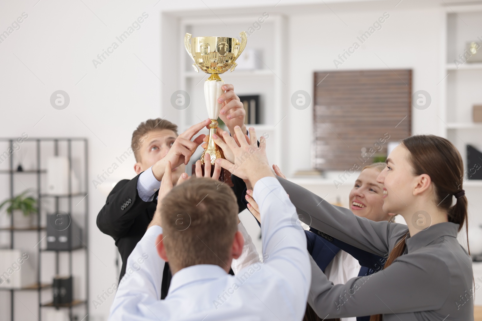 Photo of Competition concept. Group of businesspeople with golden trophy in office