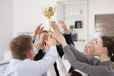 Photo of Competition concept. Group of businesspeople with golden trophy in office