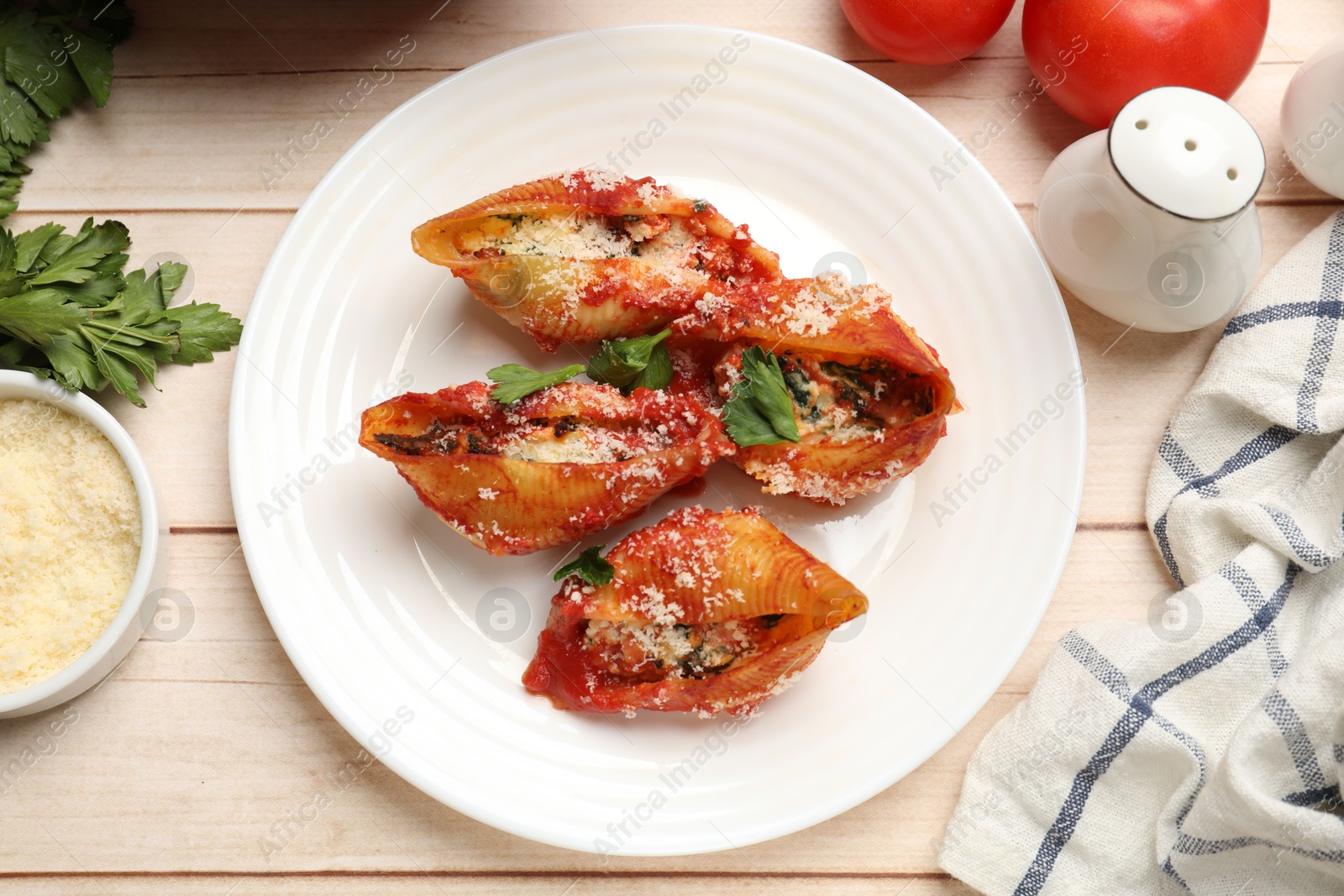 Photo of Delicious conchiglie pasta with ricotta cheese, tomato sauce and parsley on wooden table, flat lay