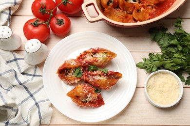 Photo of Delicious conchiglie pasta with ricotta cheese, tomato sauce and parsley on wooden table, flat lay