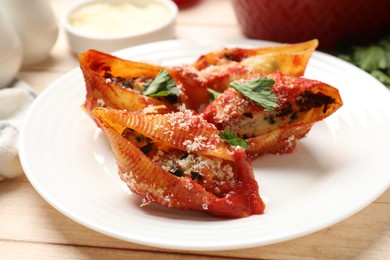 Photo of Delicious conchiglie pasta with ricotta cheese, tomato sauce and parsley on wooden table, closeup