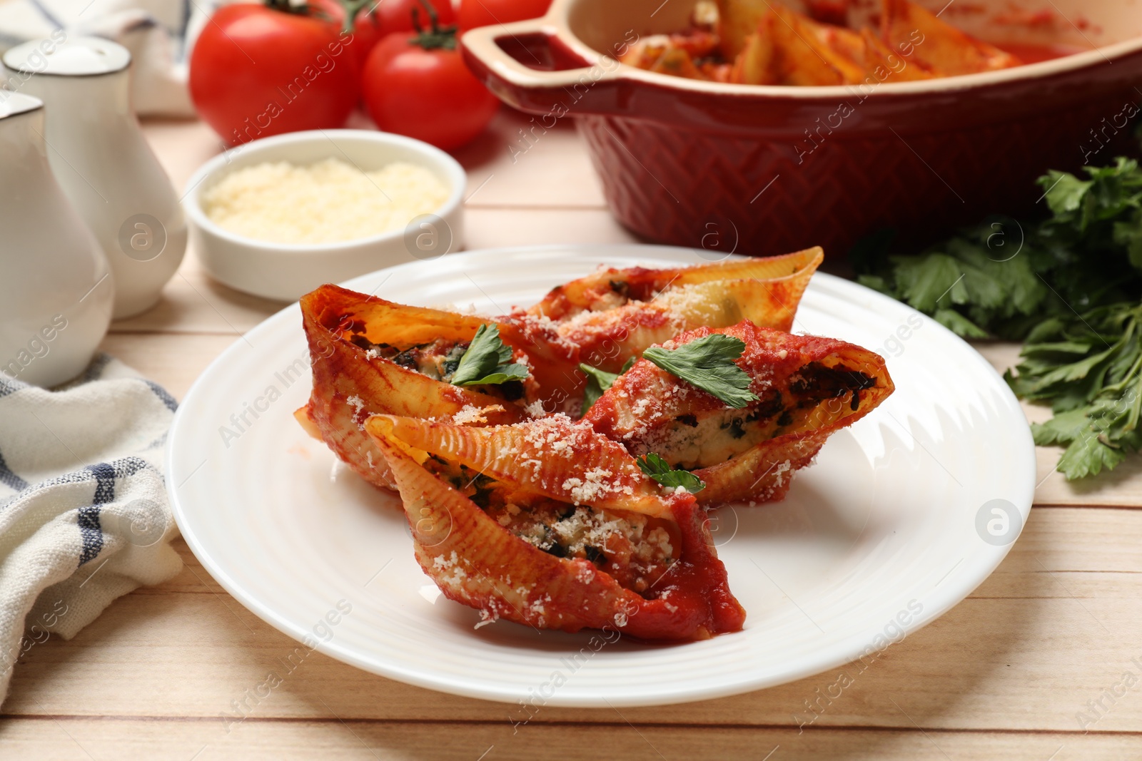 Photo of Delicious conchiglie pasta with ricotta cheese, tomato sauce and parsley on wooden table, closeup