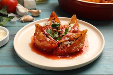 Photo of Delicious conchiglie pasta with ricotta cheese, tomato sauce and parsley on light blue wooden table, closeup