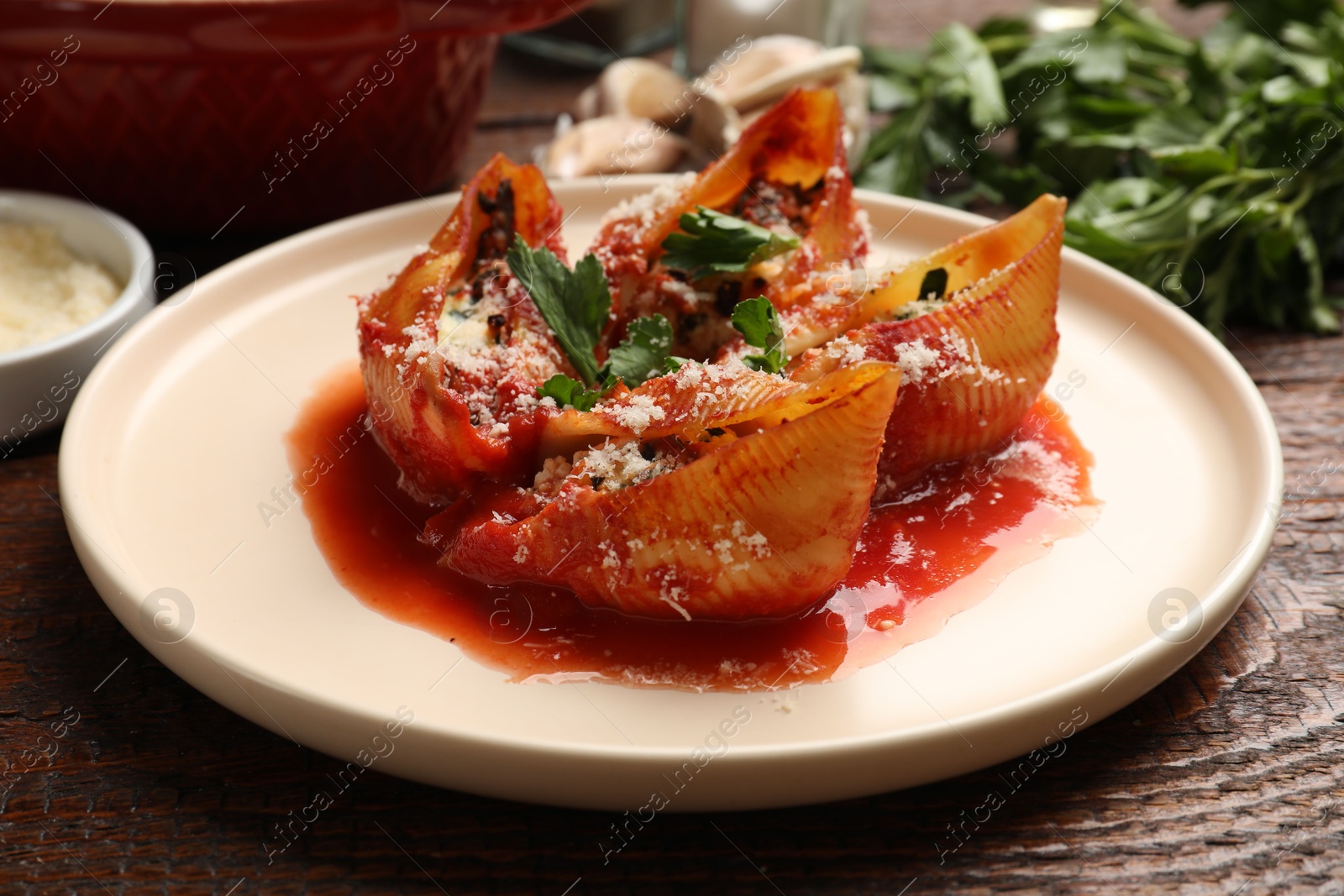 Photo of Delicious conchiglie pasta with ricotta cheese, tomato sauce and parsley on wooden table, closeup