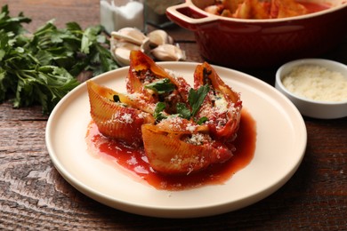 Photo of Delicious conchiglie pasta with ricotta cheese, tomato sauce and parsley on wooden table, closeup