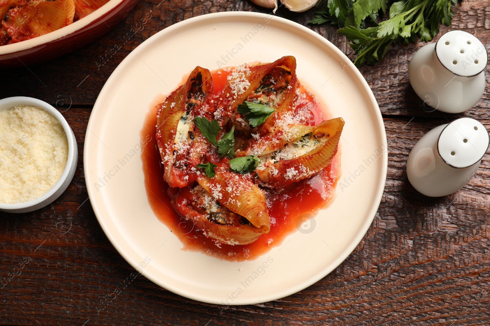 Photo of Delicious conchiglie pasta with ricotta cheese, tomato sauce and parsley on wooden table, flat lay