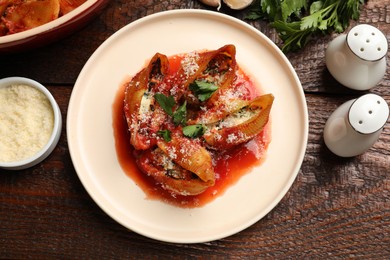 Photo of Delicious conchiglie pasta with ricotta cheese, tomato sauce and parsley on wooden table, flat lay