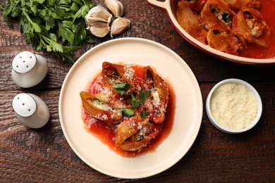 Photo of Delicious conchiglie pasta with ricotta cheese, tomato sauce and parsley on wooden table, flat lay