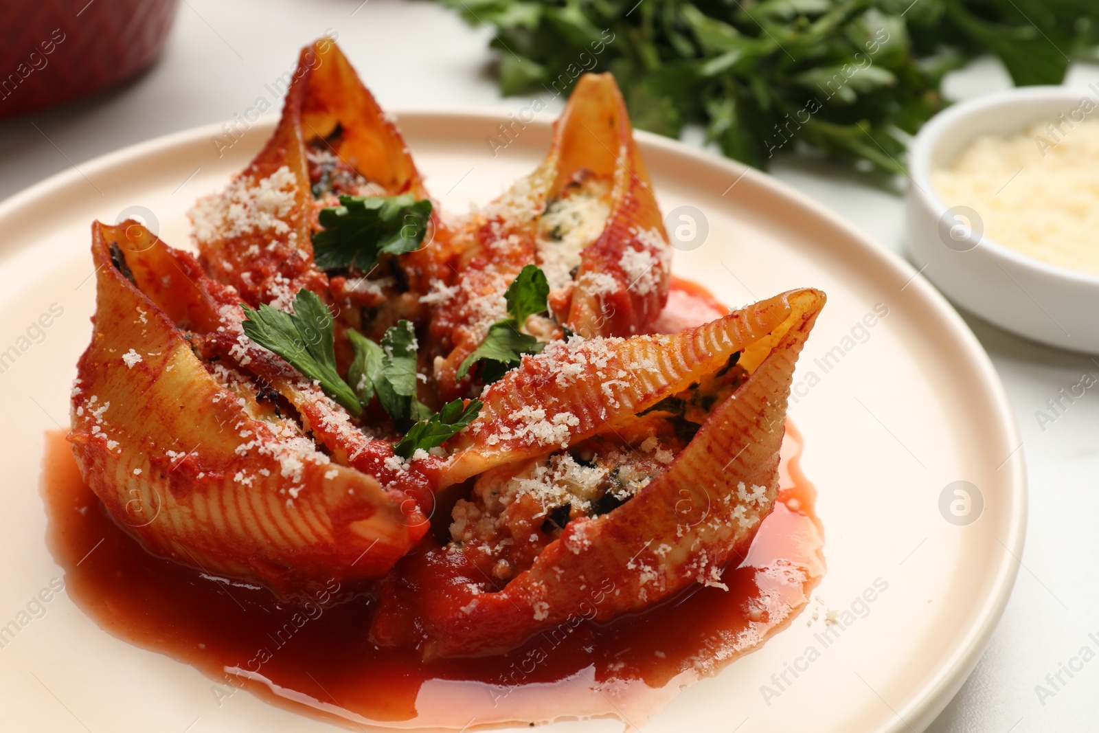 Photo of Delicious conchiglie pasta with ricotta cheese, tomato sauce and parsley on light table, closeup