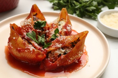 Photo of Delicious conchiglie pasta with ricotta cheese, tomato sauce and parsley on light table, closeup