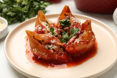 Photo of Delicious conchiglie pasta with ricotta cheese, tomato sauce and parsley on light table, closeup