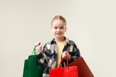 Photo of Happy little girl with shopping bags on grey background