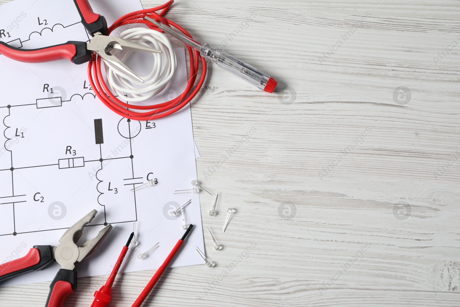 Photo of Different electrical tools and circuit diagrams on light wooden table, flat lay. Space for text